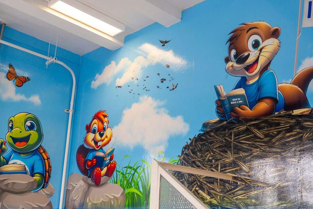 Wraparound reading-nook mural with animal characters and a sky backdrop